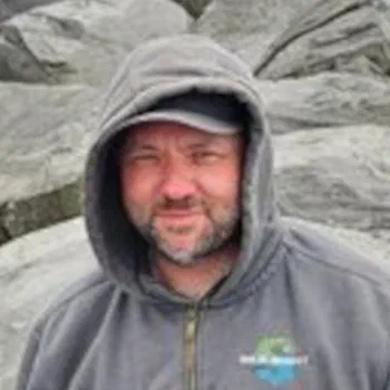 Christopher Raymond, PE, in a hooded sweatshirt in front of a rock face
