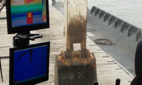 Two ClamVision monitors mounted inside a crane cab with the clamshell bucket on deck beyond the window