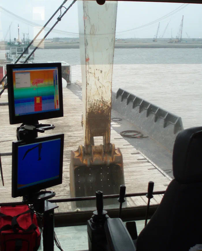 Two ClamVision monitors mounted inside a crane cab with the clamshell bucket on deck beyond the window