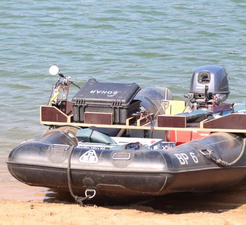 An inflatable survey skiff with a sonar case mounted on deck, pulled up on shore