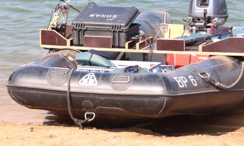 An inflatable survey skiff with a sonar case mounted on deck, pulled up on shore