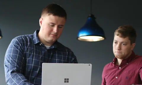 Two people reviewing survey data together on a laptop