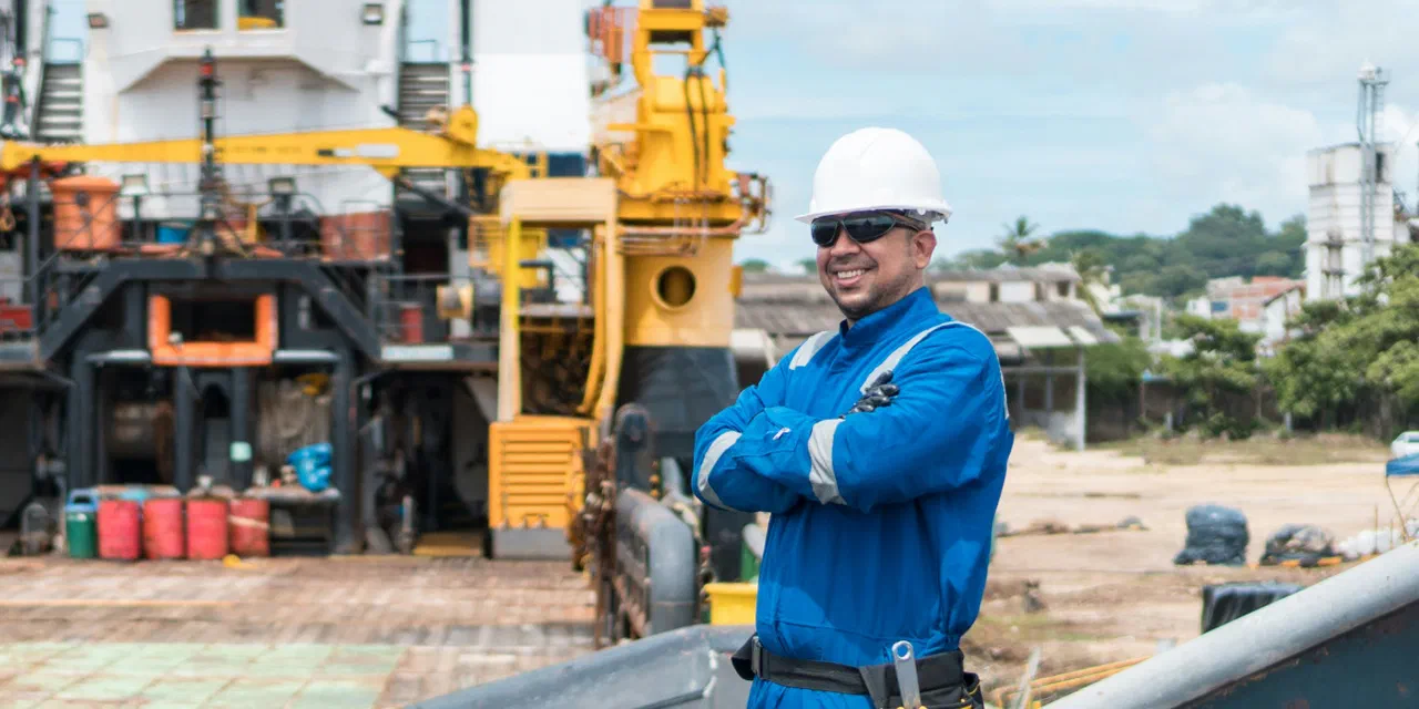 A worker in a hard hat standing on the deck of a large work vessel in port