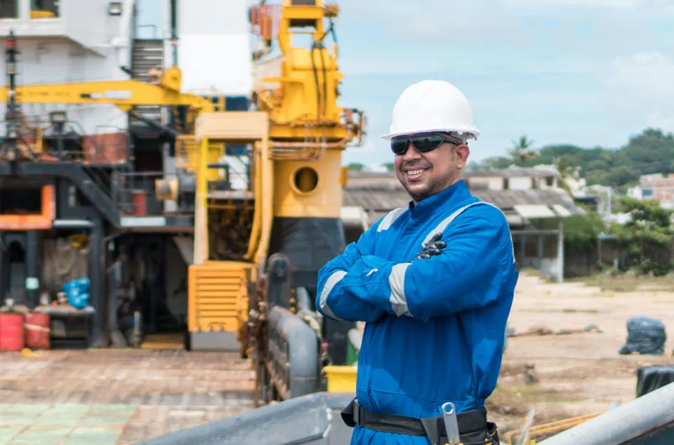 A worker in a hard hat standing on the deck of a large work vessel in port
